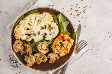 Cauliflower steak with grilled champignons and hummus, top view.