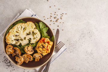 Cauliflower steak with grilled champignons and hummus, top view.