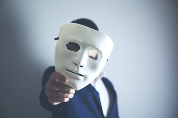 man holding white mask for hide his face