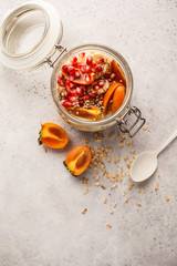 Overnight oatmeal with pomegranate, persimmon and hemp seeds, white background.