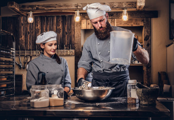 Chef mixes the ingredients for the dough. Chef teaching his assistant to bake bread in the bakery.