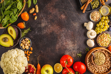 Vegan food ingredients on a dark background. Vegetables, fruits, cereals, nuts, beans top view.