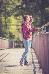 Junge Frau auf Brücke blickt der Sonne entgegen, Herbsttag