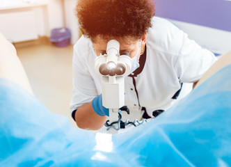 Gynecologist examining a patient with a microscope.