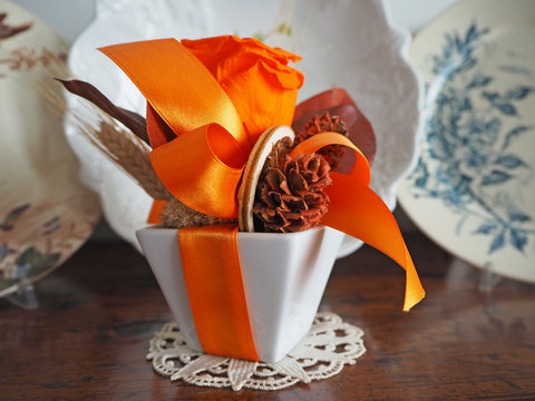Rose and orange bow in white ceramic vase