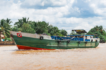 Mekong Delta, Ben Tre, Vietnam - October 21, 2016. Local man driving a traditional boat in the Mekong River Delta. Muddy tropical waters , painted wooden boats used by local fishermen.