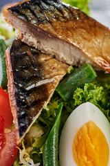A modern variation of Caesar salad. Fish salad with eggs and vegetables. A piece of meat and fish is grilled to a tasty crust. Fresh juicy cucumbers, tomatoes, lettuce, greens and asparagus.