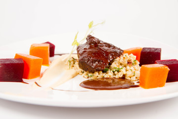 Beef cheeks with vegetables, roasted parsley root mousse , pearl barley, dark chocolate and demi glace sauce on a white background