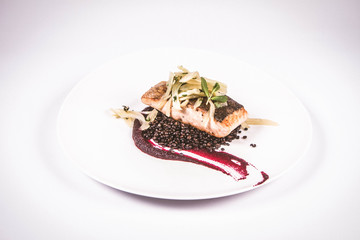 Baked salmon, beetroot mousse, black lentils and pear on a white background