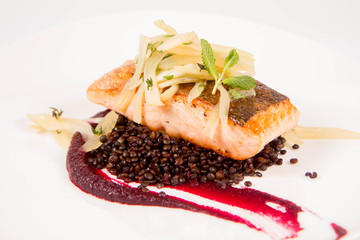 Baked salmon, beetroot mousse, black lentils and pear on a white background