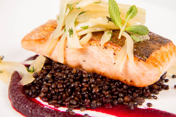 Baked salmon, beetroot mousse, black lentils and pear on a white background