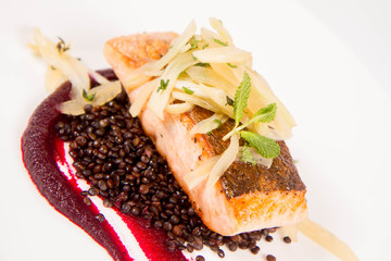 Baked salmon, beetroot mousse, black lentils and pear on a white background