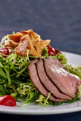 A hearty nice salad for the festive table. Slices of salted meat, bacon, beef, veal, pork from oven, meat sausage, ham. Appetizer from greenery, arugula, mushrooms chanterelles and cherry tomatoes.