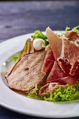 Expensive Italian, Spanish, French salad for festive table. Snack from pear, mozzarella, jamon, greens, lettuce, sauce. Cuisine of France, Spain, Italy. Photo of food for menu, cookbook, culinary blog