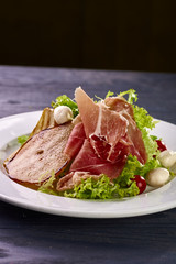 Expensive Italian, Spanish, French salad for festive table. Snack from pear, mozzarella, jamon, greens, lettuce, sauce. Cuisine of France, Spain, Italy. Photo of food for menu, cookbook, culinary blog