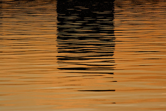 Beautiful reflections on the water before sunset in orange and dark colors  &ndash; background image, Moscow river, Russia