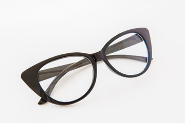 Pair of reading glasses or spectacles with modern dark frames folded up on a white background