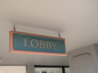 Green and gold lobby sign hanging outside at entrance of hotel