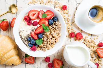 Granola with berries, yoghurt, croissant and coffee cup for breakfast. Cereal oats with strawberries, blueberries and raspberries for healthy eating. Top view