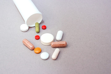 Tablets and pills from a bottle on a gray background