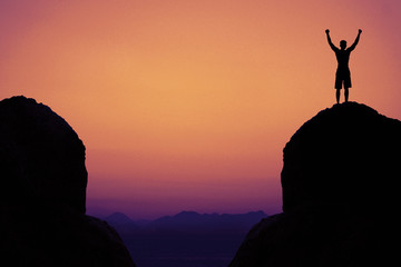 Silhouette of a cheering man in mountains as symbol for success