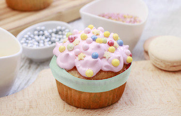 Pink muffins decorated with colorful sprinkles.
