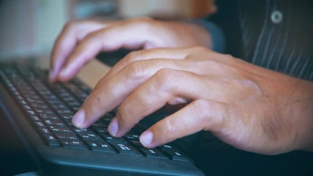 man typing on the keyboard. hands of a young man close up