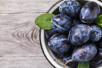 Full plate of ripe prune fruits on wooden table with copy space, top view