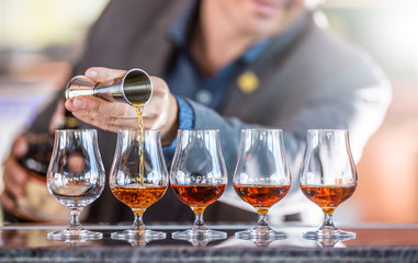Bartender professional preparing five alcololic drinks.