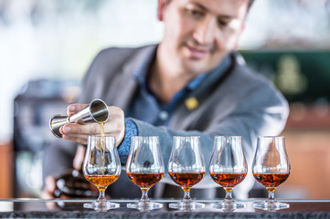 Bartender professional preparing five alcololic drinks.