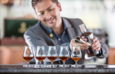 Bartender professional preparing five alcololic drinks.