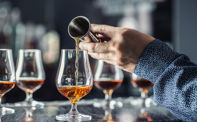 Bartender hand pouring alcoholic drink in nightclub, bar or pub.