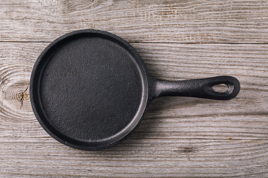 Empty cast-iron frying pan on wooden table, top view