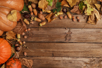Autumn composition with dry leaves and ripe pumpkins on a wooden table. Top view. Copy space