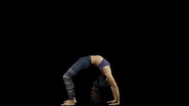 amazing female yoga instructor moving between back bend poses against black background
