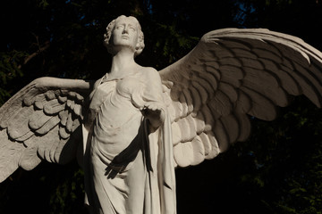 Marble Statue of a winged Angel on a Tombstone at a Berlin Cemetry