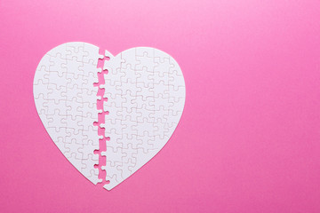 Fototapeta premium White puzzle heart on pink background. Missing piece. Top view