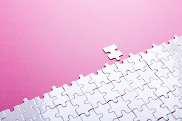 White puzzle on pink background. Missing piece. Top view