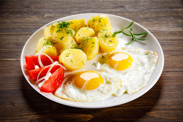 Fried eggs, boiled potatoes and vegetables
