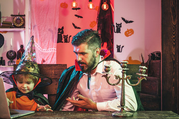 Online shopping. Holiday family concept. The father helps the child to buy goods for Halloween...