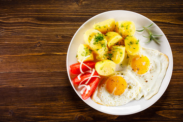 Fried eggs, boiled potatoes and vegetables