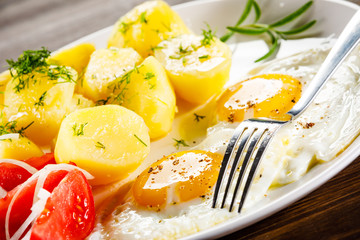 Fried eggs, boiled potatoes and vegetables