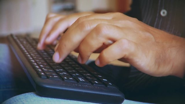 man typing on the keyboard. hands of a young man close up
