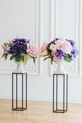 Decoration for wedding ceremony. Natural flowers in white vases on stand isolated over white background. Vertical indoor shot. Beautiful roses.