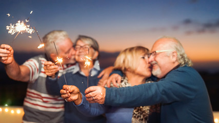 Happy senior friends celebrating with sparklers outdoor - Older people having a fun and tender...