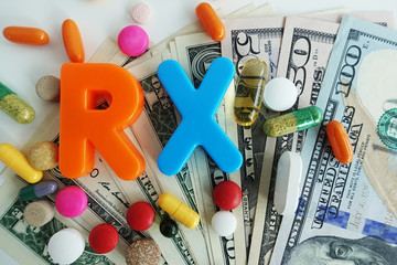 RX pills and drugs prices concept with colorful pharmaceutical tablets on cash us dollars...