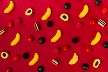 Variety of colorful candy pattern on red background.