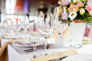 Table at a luxury wedding reception. Beautiful flowers on the table. Serving dishes, glass glasses, waiters work,