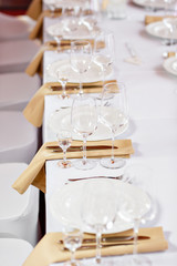 Table at a luxury wedding reception. Beautiful flowers on the table. Serving dishes, glass glasses, waiters work,