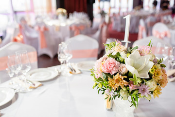 Round table at a luxury wedding reception. Beautiful flowers on the table. Serving dishes, glass glasses, waiters work,